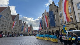 Menschen, die in einer langen Reihe stehen und blau-gelbe Flaggen halten