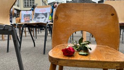 Eine Rose liegt auf einem Holzstuhl.