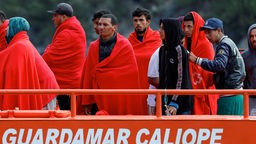 Migranten warten im Hafen von Arguineguin darauf, von einem Schiff der spanischen Küstenwache auszusteigen