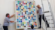 Mitarbeiter hängen das Bild «192 Farben» von Gerhard Richter in der Kölner Filiale des Versteigerungshauses Sotheby's auf. 