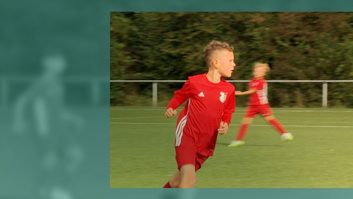 Ein Junge läuft auf dem Fußball-Platz nach rechts