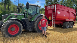 Mann vor einem Traktor mit Anhänger 