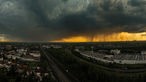 Dunkle Wolken und orangefarbener Himmel durch die darüber scheinende Sonne über dem Duisburger Süden