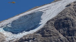 04.07.2022, Italien, Canazei: Ein Rettungshubschrauber überfliegt den Gletscher Punta Rocca in der Nähe von Canazei in den italienischen Alpen