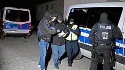 Polizisten führen bei einer Razzia im Clanmilieu in Solingen einen Verdächtigen ab.