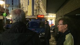 Personen vor einem Polizeiwagen 