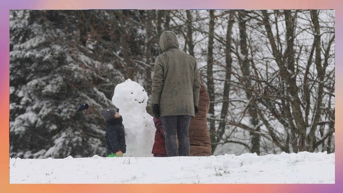 Spaziergänger bauen einen Schneemann