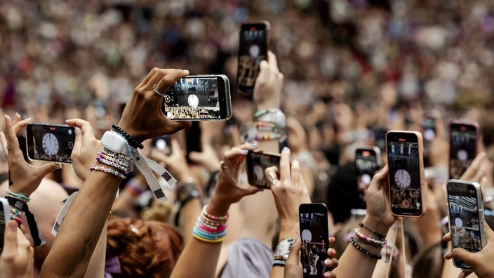 Fans halten ihre Smartphones auf einem Konzert nach oben um zu filmen