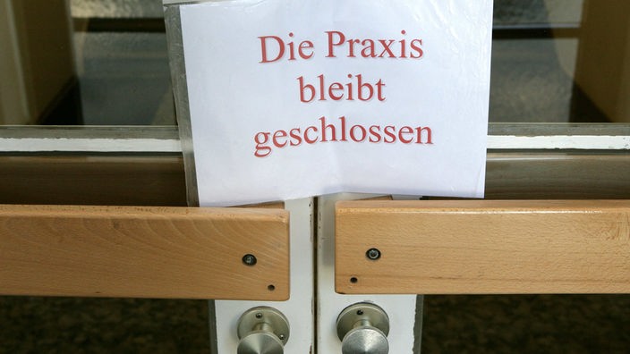 An der Tür einer Hausarztpraxis hängt ein Schild mit der Aufschrift "Praxis vorübergehend geschlossen"