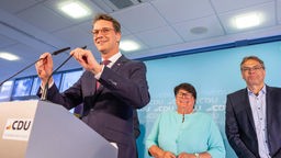 Hendrik Wüst (CDU), steht bei der Wahlparty seiner Partei auf der Bühne. Im Hintergrund stehen Sabine Verheyen und der Spitzenkandidat Peter Liese