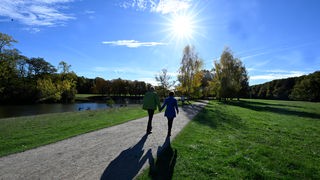 Spaziergänger nutzen den Sonnenschein und die warmen Temperaturen für einen Spaziergang durch den Kölner Grüngürtel am Denksteiner Weiher.