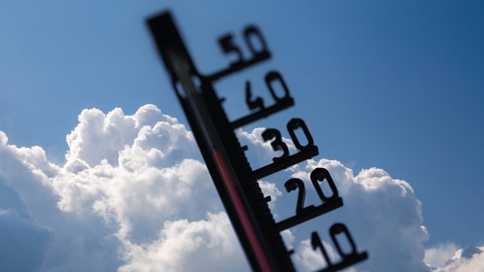 Hitze/Unwetterwarnung: Thermometer vor sich aufbauenden Quellwolken