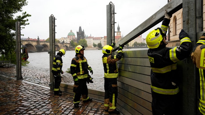 Feuerwehrleute stellen am Freitag, 13. September 2024, Teile einer Hochwasser-Schutzwände in Prag auf.