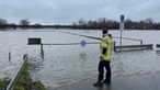 Ein Feuerwehrmann steht in Warendorf von einem überschwemmten Parkplatz.