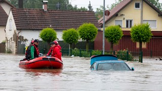 Babenhausen: Die Wasserwacht fährt mit einem Schlauchboot durch eine überflutete Straße