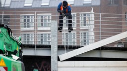 Mitarbeiter der Stadt Düsseldorf schließen das Tor am Unteren Rheinwerft zum Alten Hafen