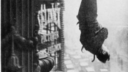 Houdini hängt kopfüber von einem Wolkenkratzer