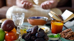 Ein traditionelles Iftar Festessen steht auf einem Tisch. Im Hintergrund beetet jemand