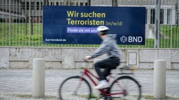 Ein Plakat der neuen Imagekampagne des Bundesnachrichtendienstes (BND) mit der Aufschrift "Wir suchen Terroristen (m/w/d)" hängt am Zaun der Zentrale des Dienstes.