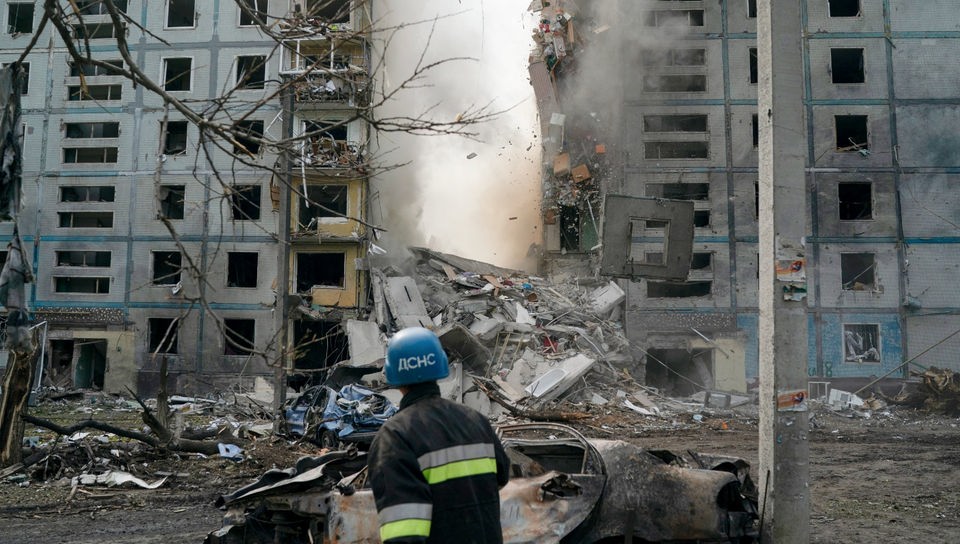 Ein Feuerwehrmann betrachtet ein zerstörtes Wohnhaus.