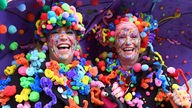 Zwei Düsseldorfer Närrinnen in bunten Kostümen lachen in die Kamera (Archivbild)