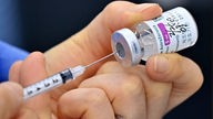 Hand zieht Impfstoff in Spritze auf.