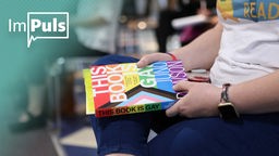 Eine Frau hält das Buch "This Book Is Gay" in der Hand