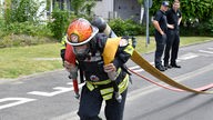 Ein Feuerwehrmann kämpft in der ersten Wettkampfstation, dem Schlauchziehen, um den Titel" Toughest Firefighter Alive"