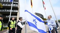 Mitarbeiter des Landtages hissen die israelische Fahne am Landtag bei einer Solidaritätskundgebung für Israel