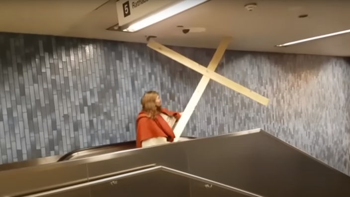 Ein als Jesus verkleideter Mann beschädigt mit einem Holzkreuz die Decke der U-Bahn Station