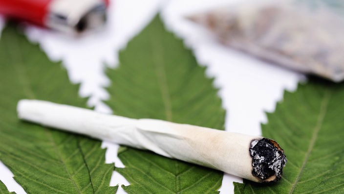 Ein Joint liegt auf einem Cannabisblatt