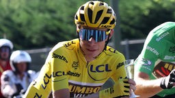 Tour de France Gewinner Jonas Vingegaard in Montur mit einem Sektglas