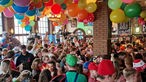 Viele Jecke feiern in einem mit bunten Ballons geschmückten Brauhaus