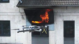 Drohne fliegt vor einem Haus, in dem es brennt