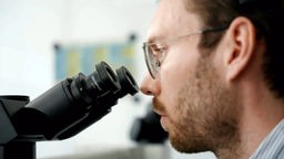 Pathologhe Julius Keil schaut durch ein Mikroskop