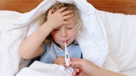 Ein Kind liegt mit Fieber im Bett