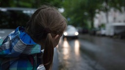 Kind steht in der Dämmerung an einer Straße