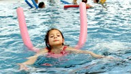Ein Kind schwimmt mit einer Schwimmhilfe