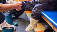 Kindergartenkind bekommt seine Socken angezogen