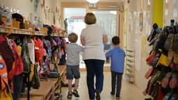 Eine Erzieherin geht im St. Michaels Kindergarten in Leinfelden-Echterdingen mit zwei Kindern über den Flur der Einrichtung