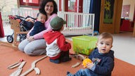 Erzieherin liest mit Kindern im "Kinderzimmer", Betreuungseinrichtung fuer Kleinkinder des Studentenwerks Bielefeld