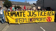 Demonstrierende mit einem großen Transparent mit der Aufschrift "Climate Justice Now"