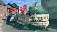 Demonstrierende des Schwarzen Blocks mit antifaschistischen und antikapitalistischen Fahnen und Pyrotechnik