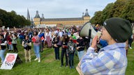 Jugendliche demonstrieren auf einer Wiese in Bonn, im Vordergrund spricht eine Person in ein Megafon