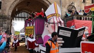 Köln: Ein Motivwagen, der Kardinal Woelki mit einem Buch mit der Aufschrift "Missbrauchsfälle" zeigen soll, fährt im Rosenmontagsumzug mit
