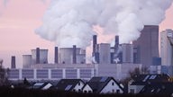 Aus den Kühltürmen des Kohlekraftwerks Niederaußem steigt in der Dämmerung Dampf auf