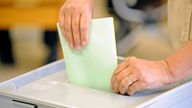 Wählerin wirft Stimmzettel in Urne