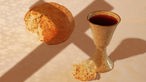 Kommunion: Ein Weinbecher und Brot liegen auf einem Tisch