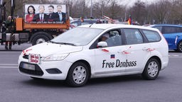 Einem Wagen mit dem Aufschrift "Free Donbass" ist bei eine Demonstration gegen die Bundesregierung in Düsseldorf auf einer Straße unterwegs.