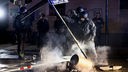Ein Polizist steht neben einer brennenden Tonne bei Protesten der linken Szene in Leipzig.